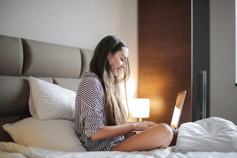 Girl sitting cross legged on bed with her laptop open in front of her