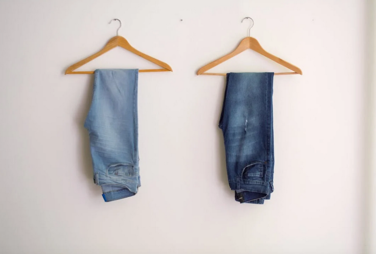 two pairs of jeans on hangers side by side