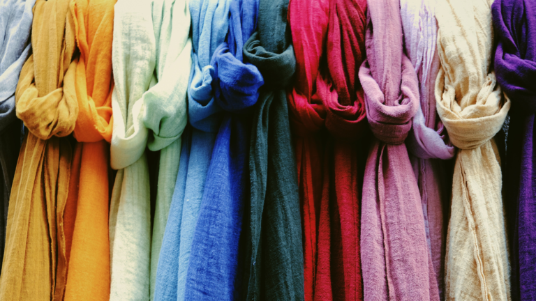 A clothing rack full of scarves in a variety of colors.