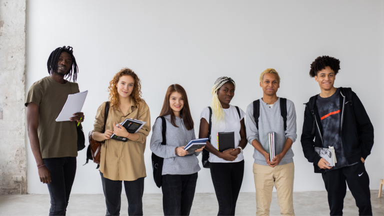 A group of college freshmen stand in front of a white wall.